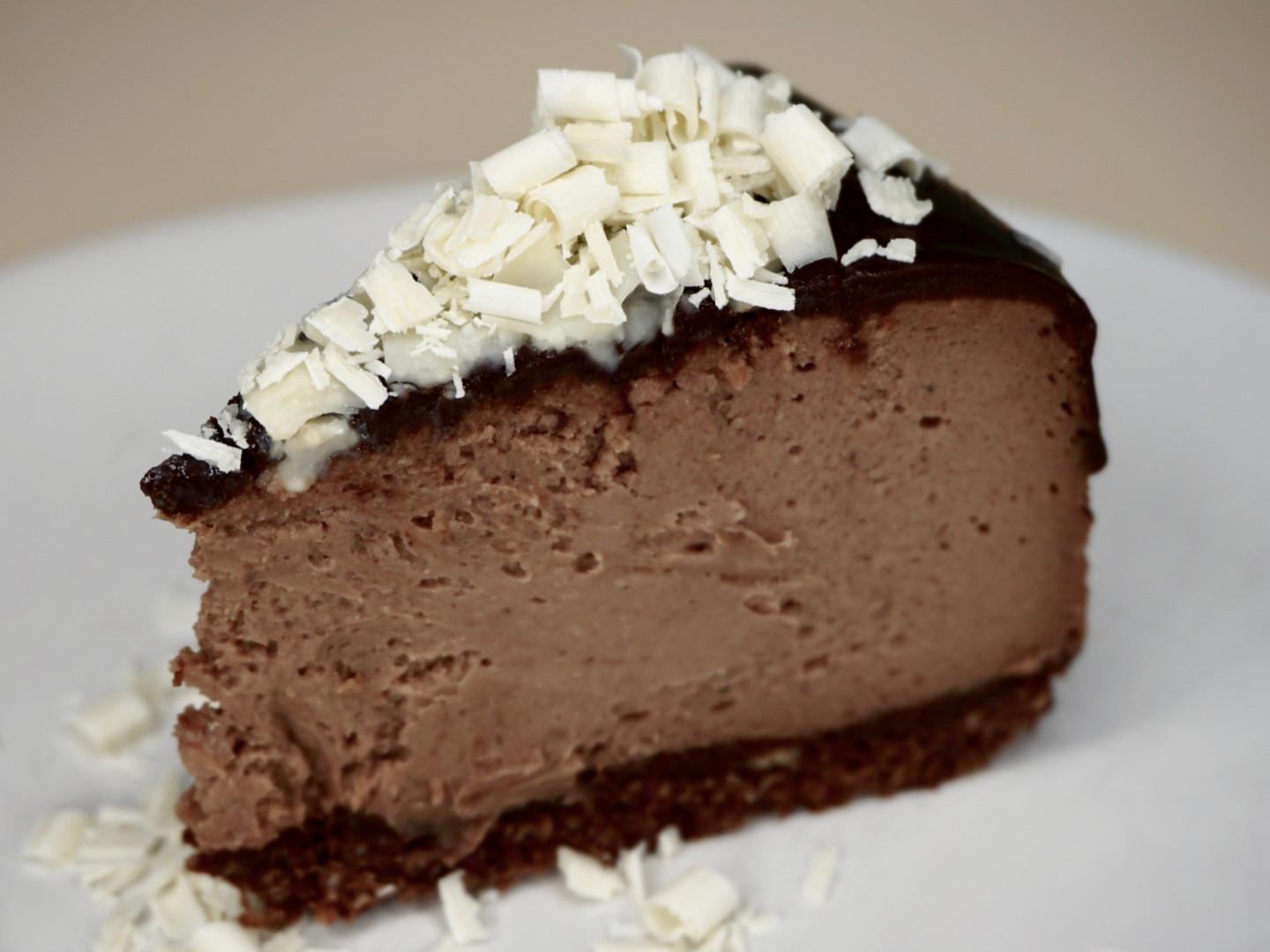 A slice of Bailey's chocolate cheesecake with Clairesquares buttery shortbread crust, topped with white chocolate curls